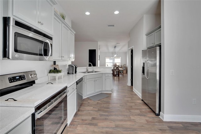 kitchen featuring sink, white cabinetry, appliances with stainless steel finishes, light hardwood / wood-style floors, and kitchen peninsula