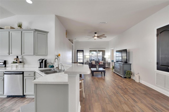 kitchen featuring kitchen peninsula, a kitchen bar, sink, hardwood / wood-style flooring, and dishwasher