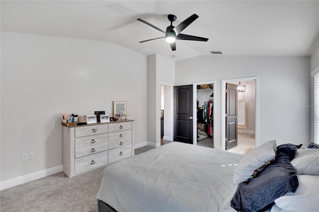 carpeted bedroom featuring a walk in closet, vaulted ceiling, ceiling fan, connected bathroom, and a closet