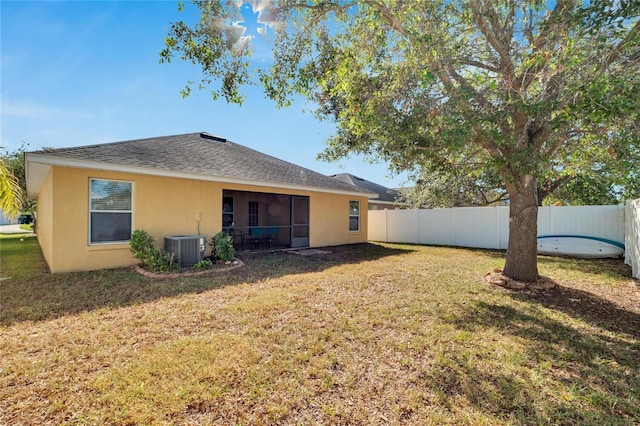 back of property with a yard and central AC