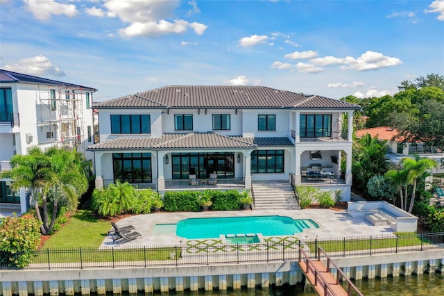 back of property featuring a balcony, a fenced in pool, a patio, and a water view