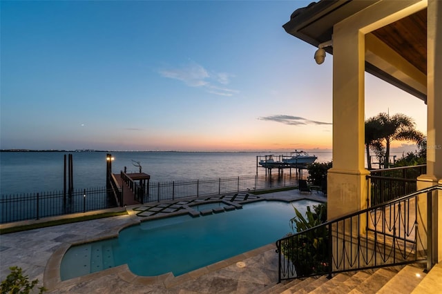 pool at dusk with a water view and a patio area