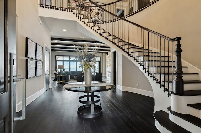 entryway with a high ceiling, dark wood-type flooring, and a notable chandelier