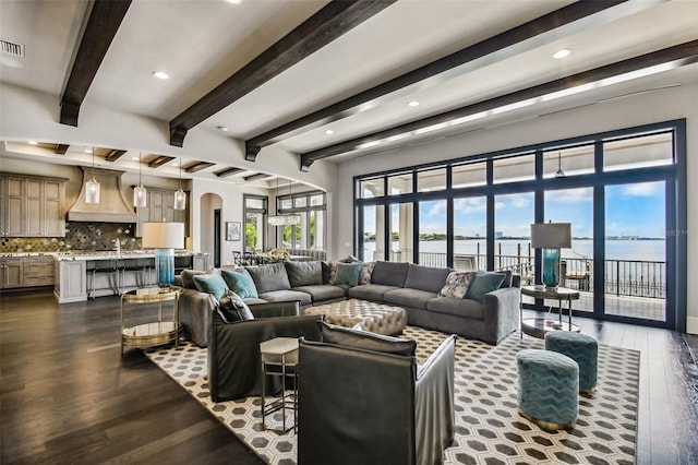 living room featuring dark hardwood / wood-style flooring, a water view, and beamed ceiling