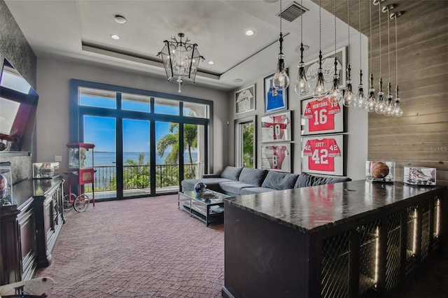 interior space featuring carpet flooring, a water view, wooden walls, and a tray ceiling