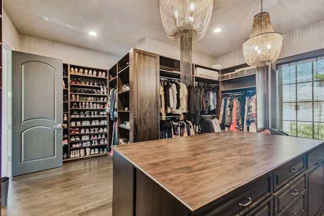 spacious closet featuring wood-type flooring and a notable chandelier