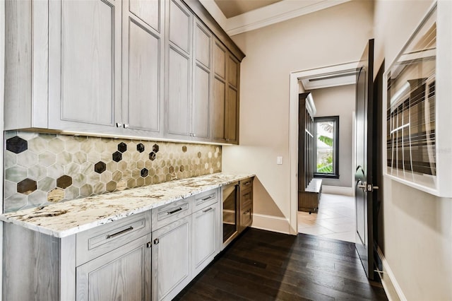 kitchen featuring tasteful backsplash, light stone counters, dark hardwood / wood-style flooring, and ornamental molding