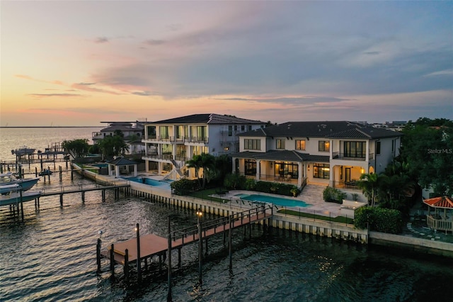 back house at dusk with a water view and a balcony