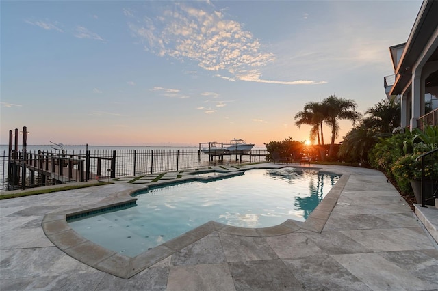 pool at dusk featuring an in ground hot tub, a water view, and a patio