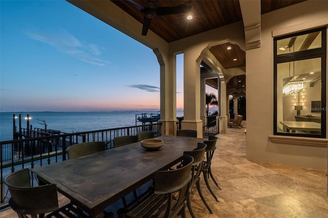 patio terrace at dusk with ceiling fan and a water view