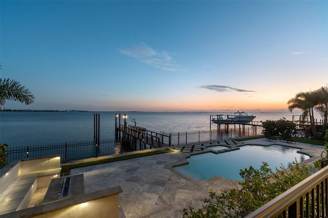 pool at dusk with a water view and a patio