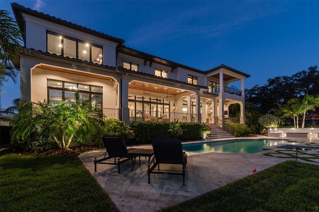 back of house with ceiling fan, a balcony, and a patio