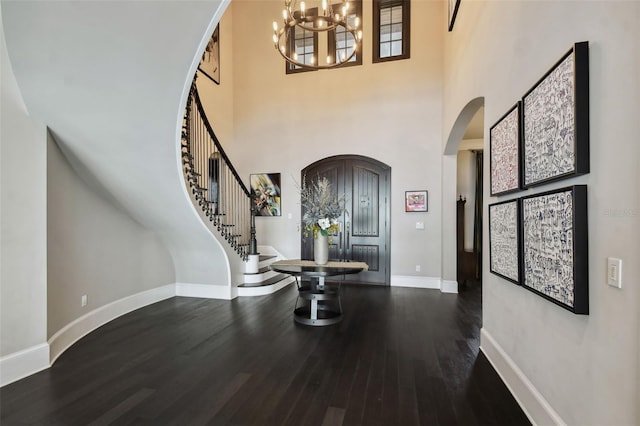 entrance foyer with dark hardwood / wood-style flooring, a high ceiling, and an inviting chandelier