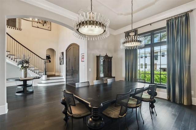 dining space with dark hardwood / wood-style flooring, ornamental molding, a high ceiling, and a notable chandelier