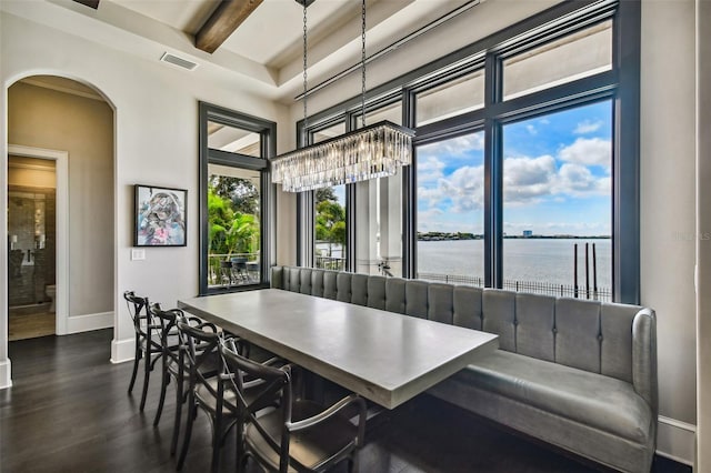 dining space with a water view and dark hardwood / wood-style floors