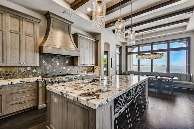 5120 W Longfellow Ave, Tampa, FL 33629 - kitchen with wall chimney range hood, arched walkways, dark wood-style flooring, a sink, and decorative backsplash
