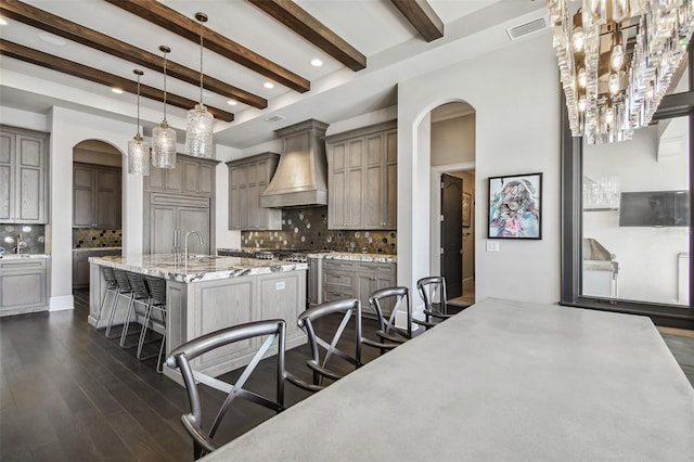 kitchen with premium range hood, decorative backsplash, a breakfast bar area, and beam ceiling