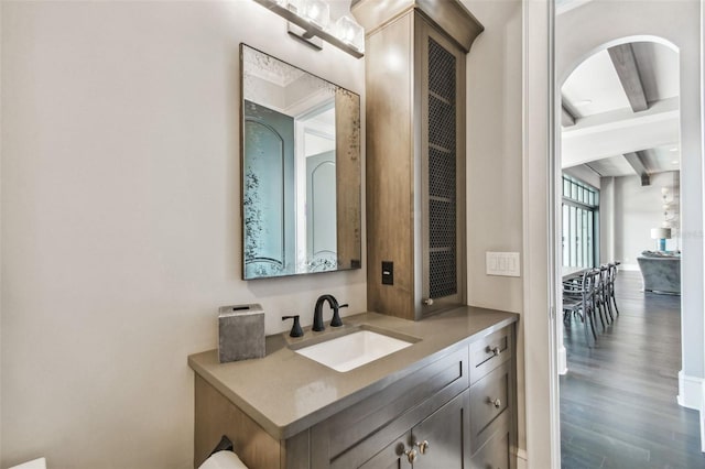 bathroom featuring beam ceiling, hardwood / wood-style floors, and vanity