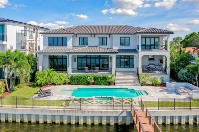 rear view of property with a balcony, a water view, and a patio area