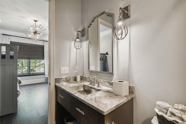 bathroom with hardwood / wood-style floors, vanity, crown molding, and a chandelier