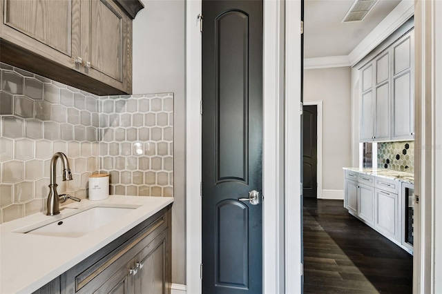 kitchen featuring decorative backsplash, ornamental molding, dark wood-type flooring, and sink