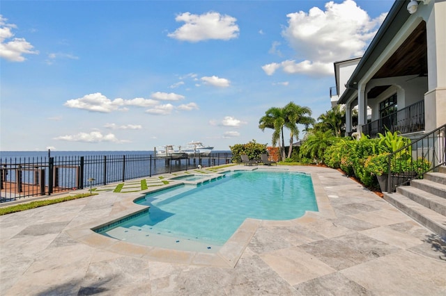 view of pool with an in ground hot tub, a water view, and a patio