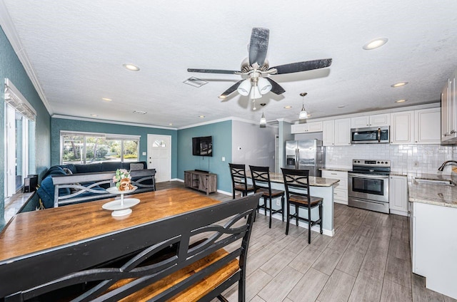 dining area with ceiling fan, ornamental molding, and sink