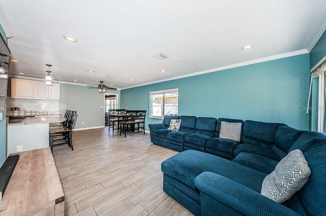 living room with ceiling fan and ornamental molding