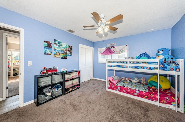 carpeted bedroom with a textured ceiling, a closet, and ceiling fan