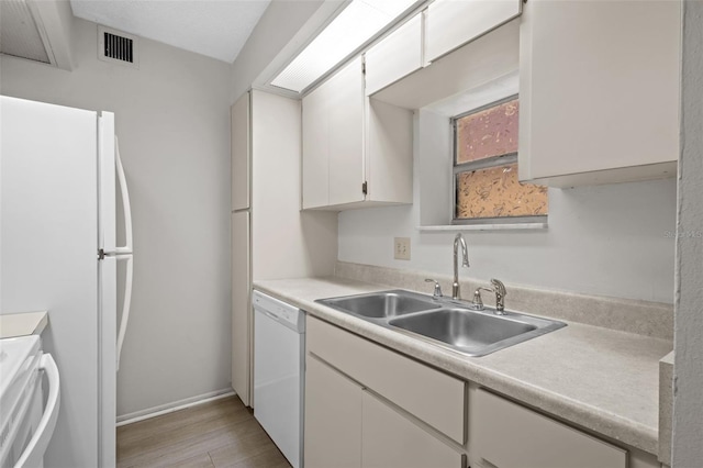 kitchen with sink, white cabinets, white appliances, and light wood-type flooring