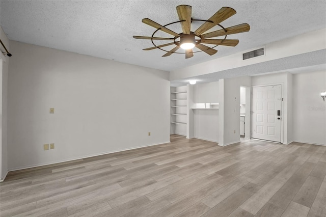 unfurnished living room with ceiling fan with notable chandelier, a textured ceiling, and light wood-type flooring