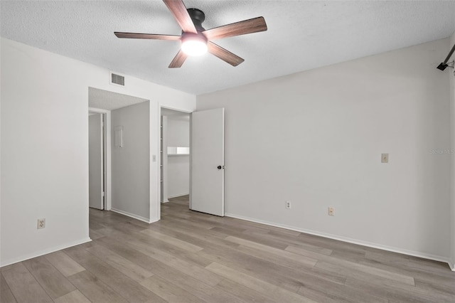 unfurnished room with ceiling fan, a textured ceiling, and light wood-type flooring