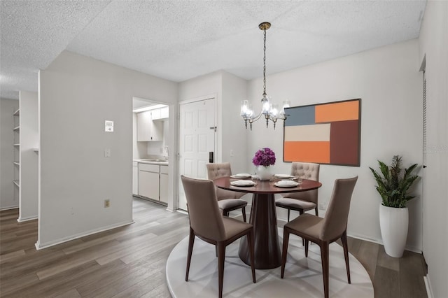 dining area with hardwood / wood-style floors, a chandelier, a textured ceiling, and sink