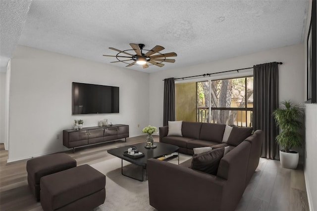 living room featuring ceiling fan, light wood-type flooring, and a textured ceiling