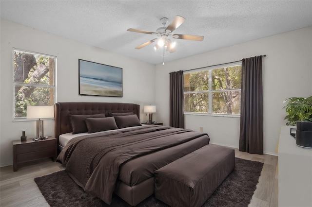 bedroom featuring ceiling fan, light wood-type flooring, and a textured ceiling