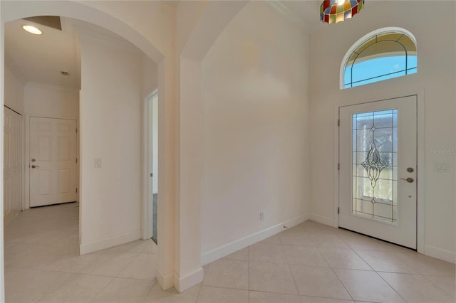 entryway with light tile patterned floors and ornamental molding