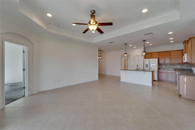 unfurnished living room featuring a tray ceiling, ceiling fan, and crown molding