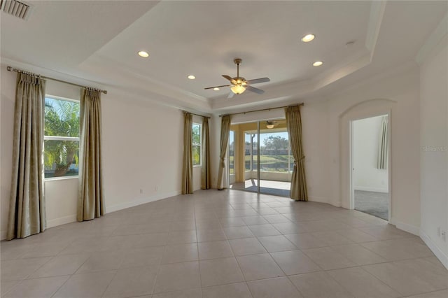 tiled spare room featuring plenty of natural light, ceiling fan, and a tray ceiling