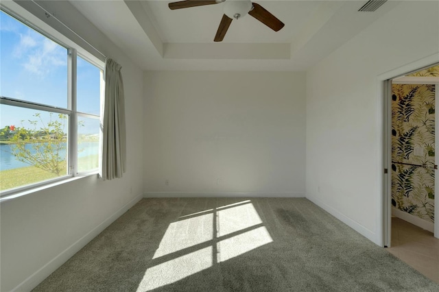 unfurnished room featuring light colored carpet, a healthy amount of sunlight, and a water view