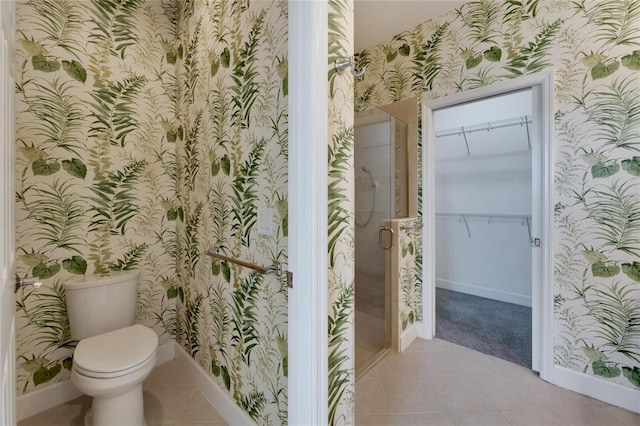 bathroom with tile patterned flooring, toilet, and a shower with shower door