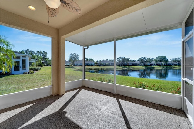 unfurnished sunroom featuring ceiling fan and a water view