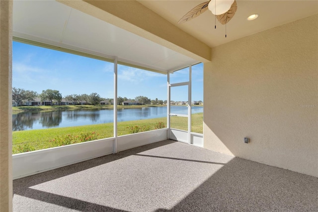 unfurnished sunroom featuring ceiling fan and a water view