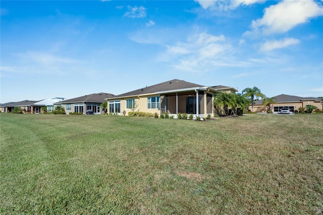 rear view of property with a yard and a sunroom