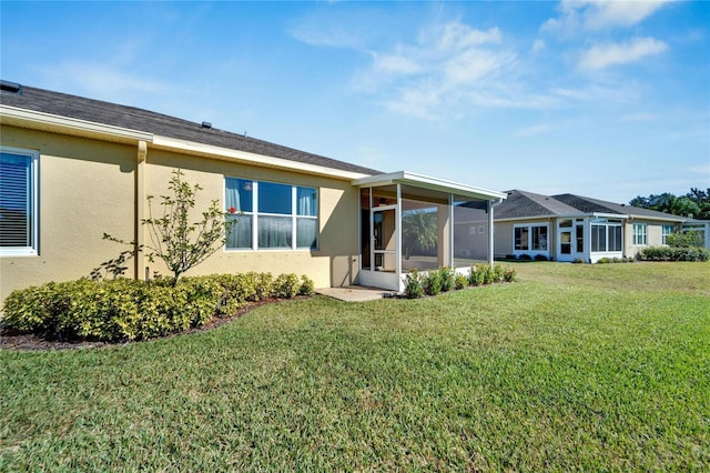 rear view of property featuring a lawn and a sunroom