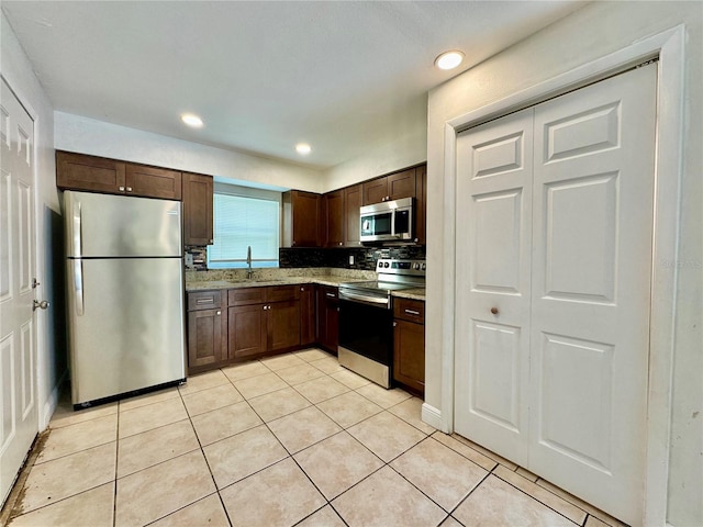 kitchen with backsplash, sink, light tile patterned floors, appliances with stainless steel finishes, and dark brown cabinets