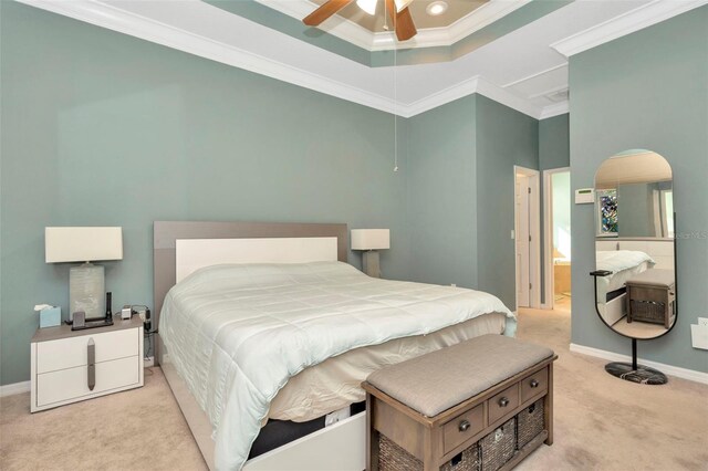 bedroom with ceiling fan, light colored carpet, ornamental molding, and a tray ceiling