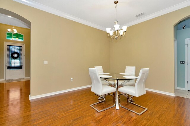 dining room featuring an inviting chandelier, crown molding, and wood-type flooring