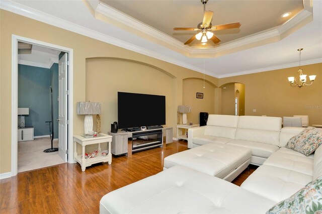 living room featuring a raised ceiling, crown molding, ceiling fan with notable chandelier, and hardwood / wood-style floors