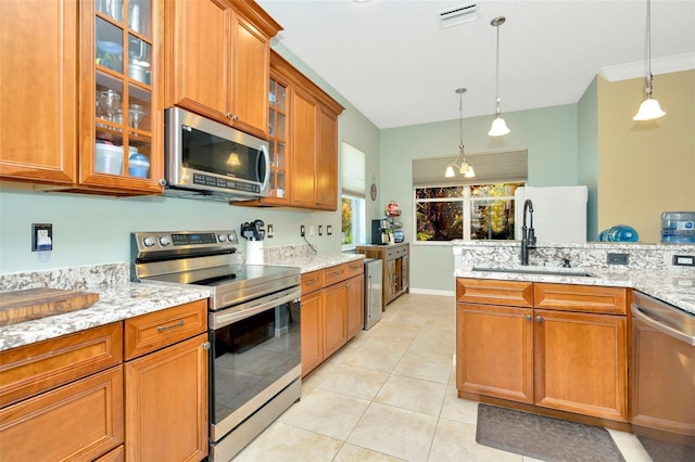 kitchen featuring sink, decorative light fixtures, light stone countertops, and appliances with stainless steel finishes