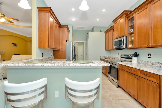 kitchen featuring light tile patterned floors, a breakfast bar area, stainless steel appliances, light stone countertops, and kitchen peninsula